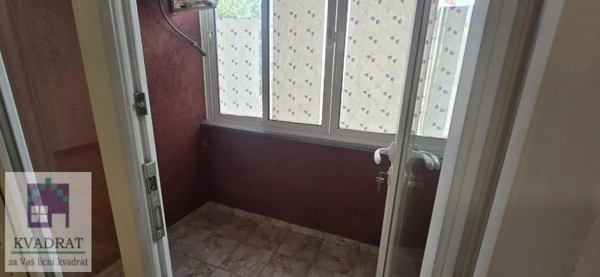 Manji zatvoreni balkon sa popločanim podom i prozorima.