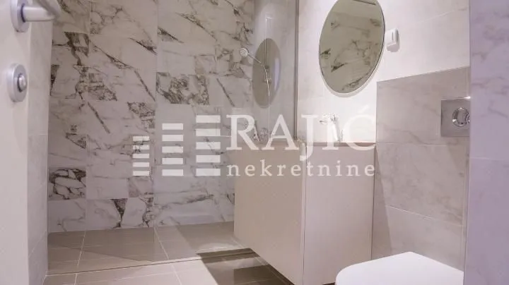 Modernly equipped bathroom with marble tiles and a walk-in shower.