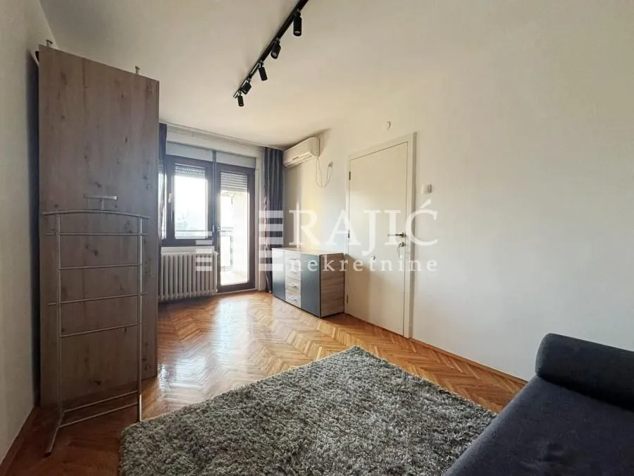 Living room with parquet flooring, a rug, and a wardrobe.