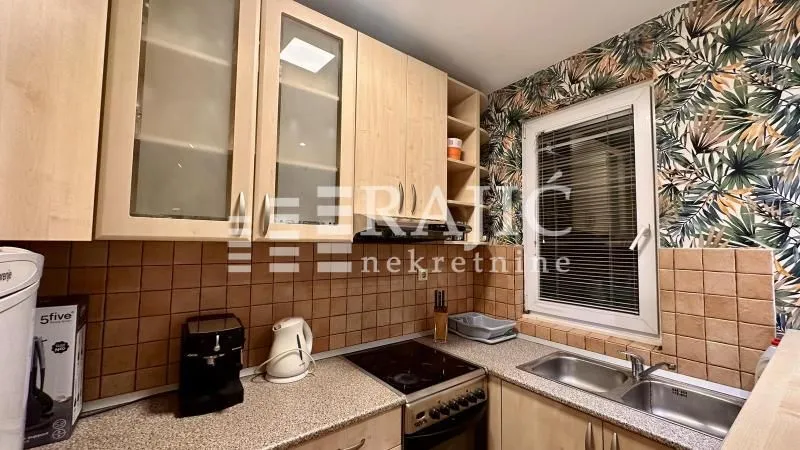 Small kitchen with wooden cabinets, sink, and built-in stove.