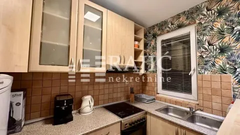 Small kitchen with wooden cabinets, sink, and built-in stove. - image 3