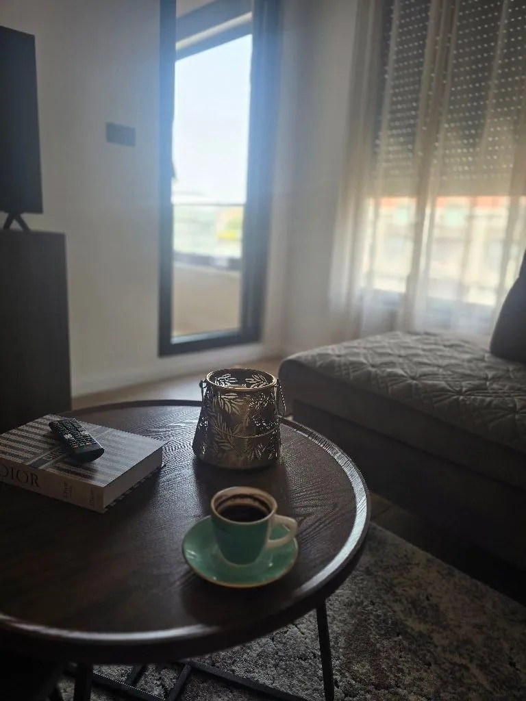 Living room with a coffee table, coffee cup, and couch by the window.