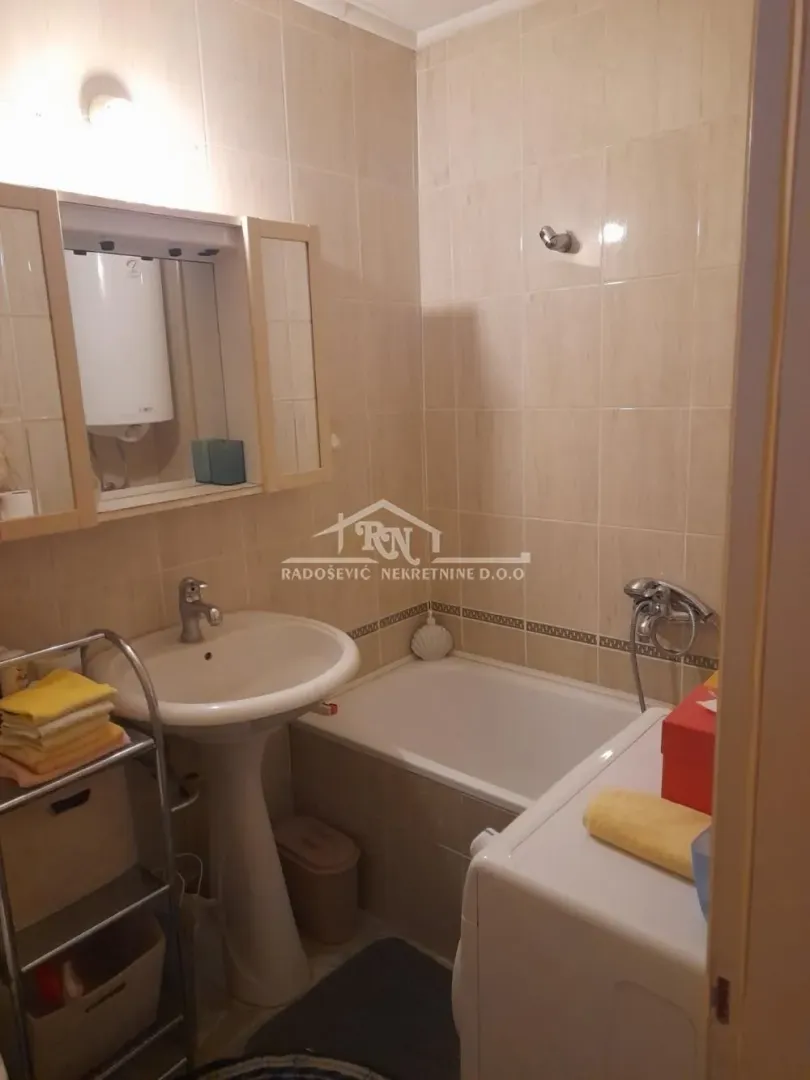 Compact bathroom with a sink, bathtub, and water heater.