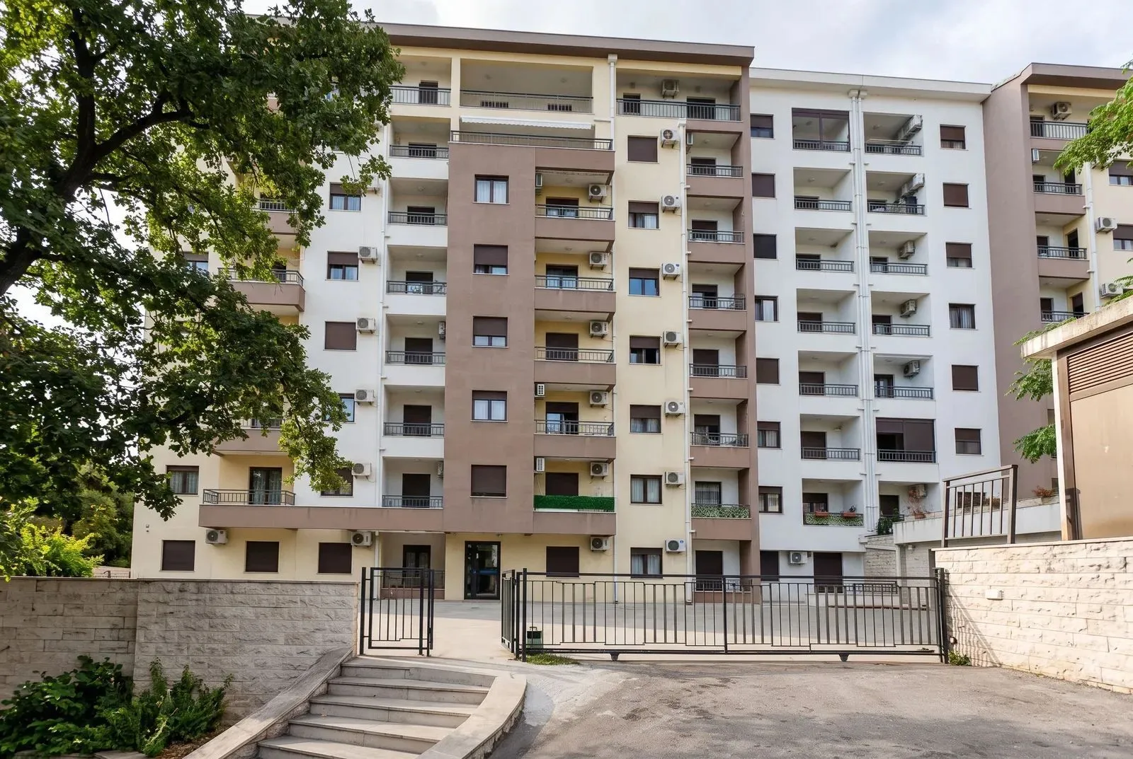 Exterior view of the apartment building with a gate and courtyard.