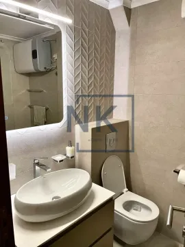 Modern bathroom with a washbasin, toilet, and backlit mirror. - image 12