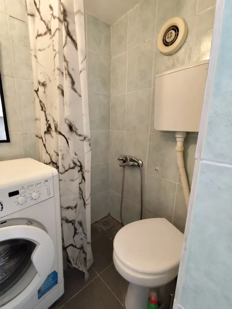 Manje kupatilo sa tuš kabinom, WC šoljom i veš mašinom.