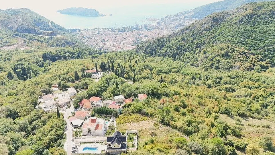 Pogled iz vazduha na prirodu, naselje i grad u daljini.