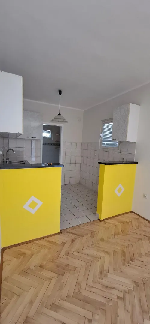 Kuhinja sa elementima i šankom u svijetlim tonovima.
