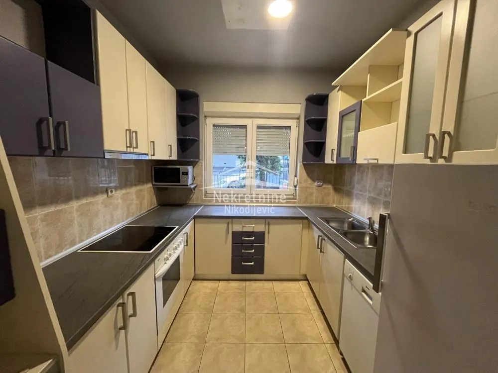 Separate kitchen with upper and lower kitchen cabinets and a window.
