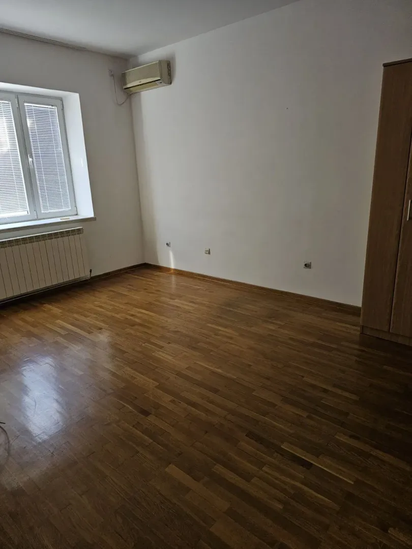 Svijetla prazna soba sa parketom, klima uređajem i ormarom.