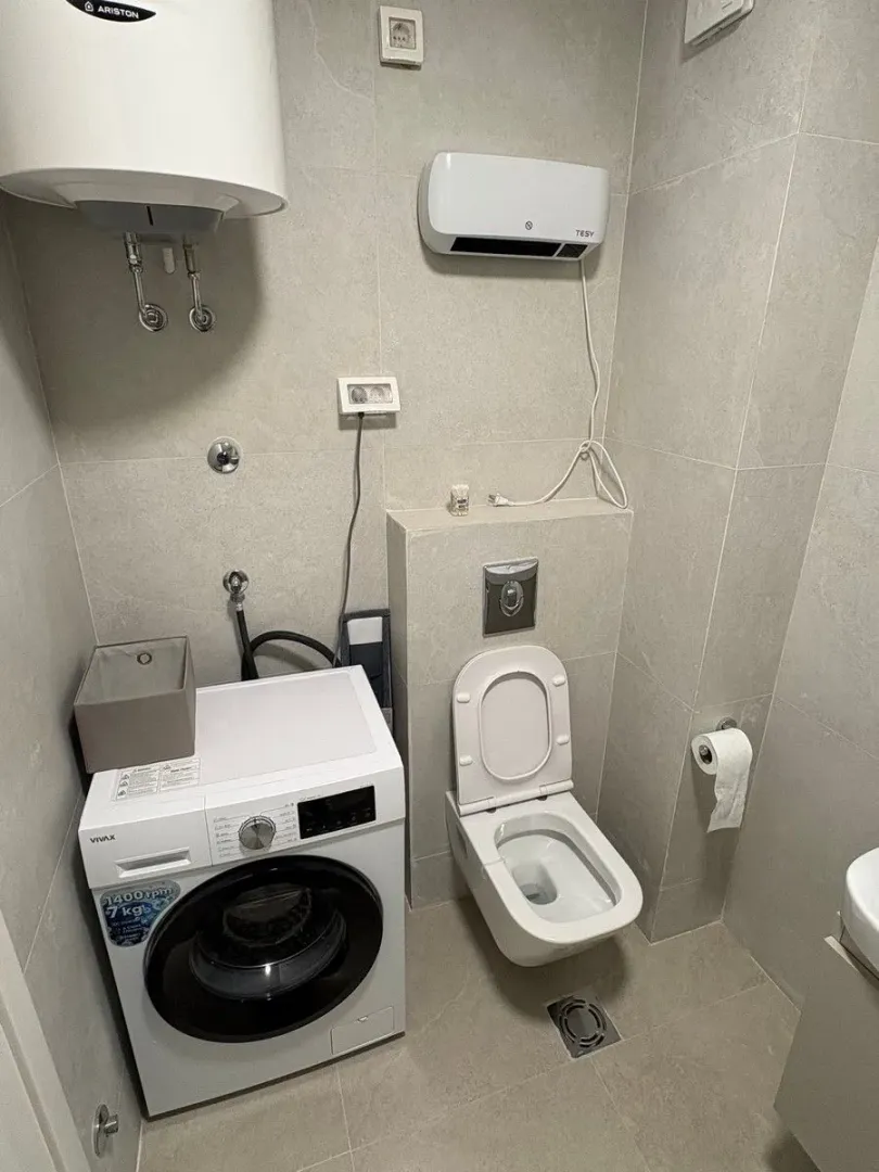 Manje kupatilo sa veš mašinom, WC šoljom i bojlerom.