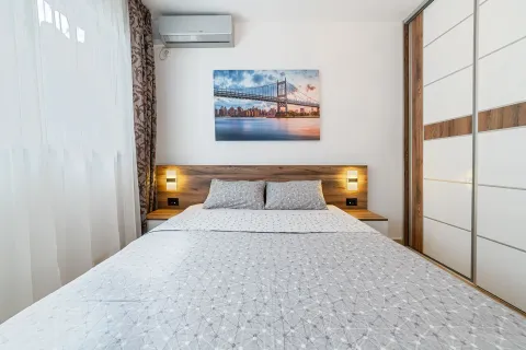 Modern bedroom with a double bed, built-in wardrobe, and air conditioning. - image 7