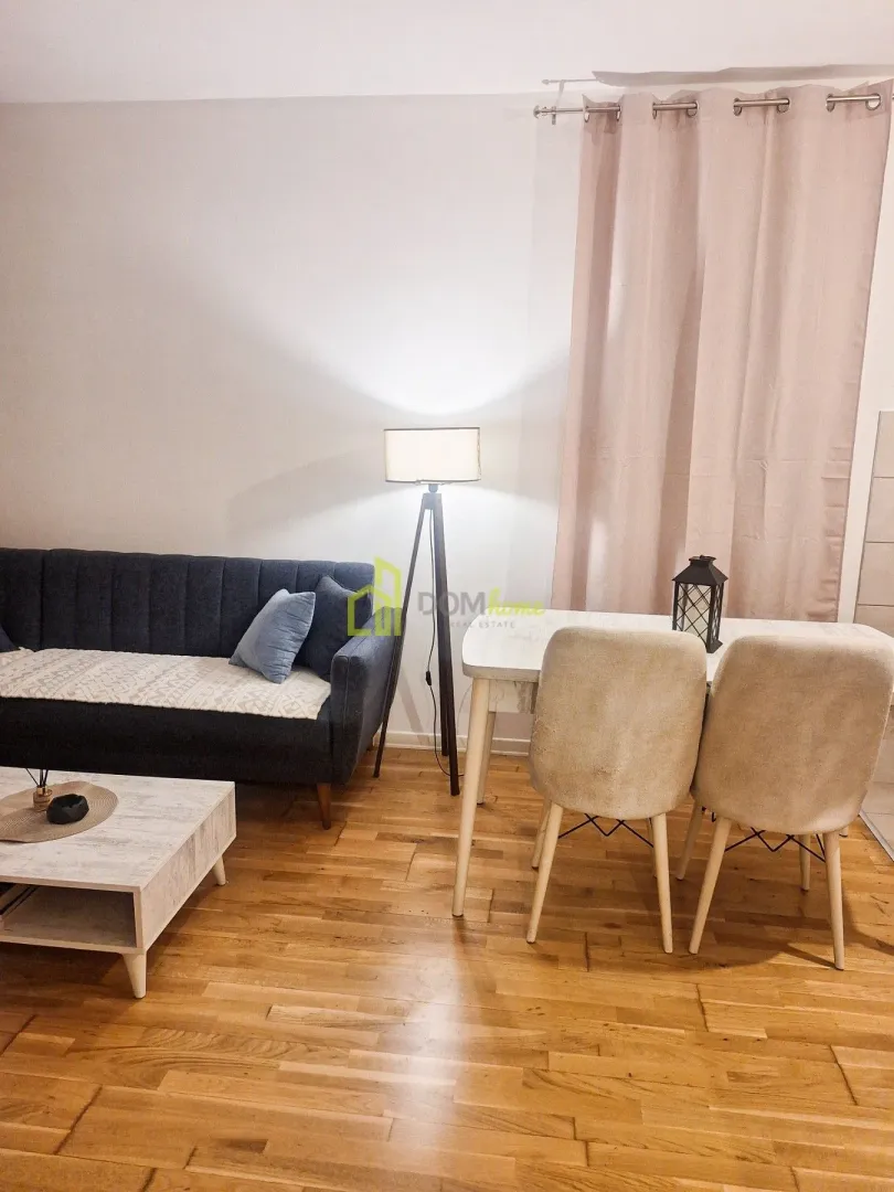 Dnevna soba sa garniturom, trpezarijskim stolom i podnom lampom.