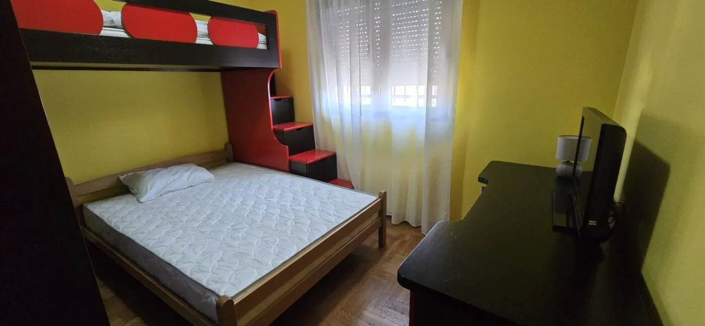 Children's bedroom featuring a bunk bed and a desk with a TV.
