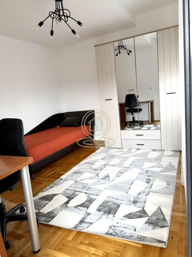 Furnished bedroom with a bed, large wardrobe and desk.