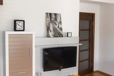 Detalj dnevnog boravka sa TV-om, policama i satovima. - image 3