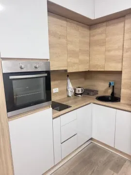 Kuhinja opremljena bijelim elementima i detaljima u boji drveta sa ugrađenom rernom. - image 5