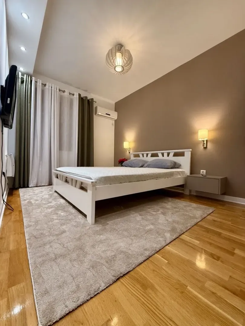 Furnished bedroom with a double bed, rug, and wall lamps.