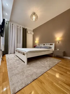 Furnished bedroom with a double bed, rug, and wall lamps. - image 7