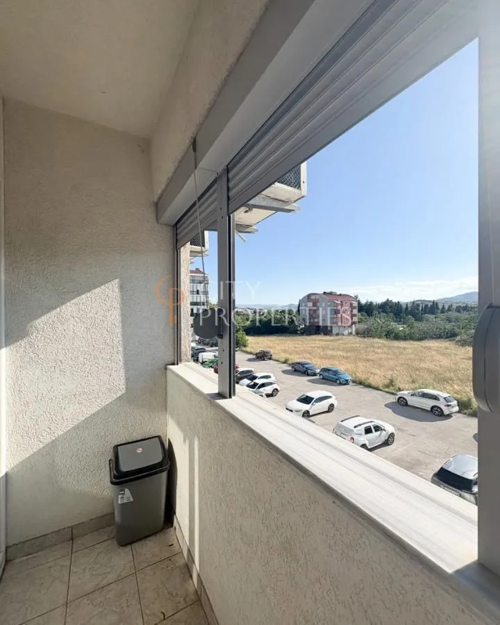 Manji balkon sa pogledom na parking i okolne zgrade.