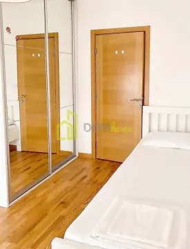 Spavaća soba sa krevetom, velikim garderoberom sa ogledalom i drvenim podom. - image 7