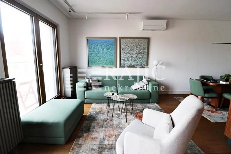 Living room with a sofa, armchair, and dining area.