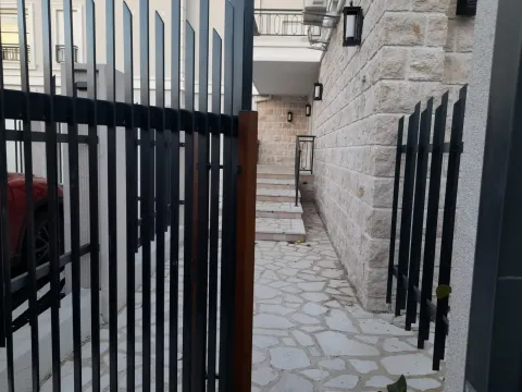 A paved entrance path with a metal fence leading to a stone-clad building. - image 4