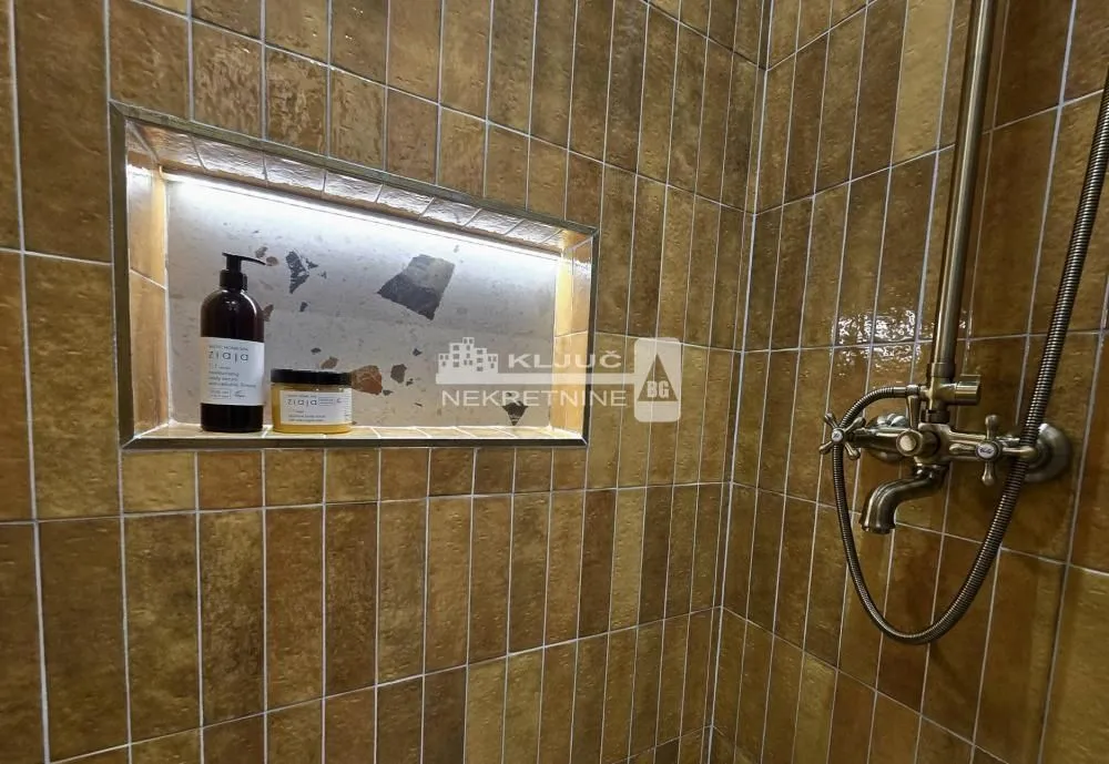 Detail of the shower cabin with yellow tiles and a built-in niche.