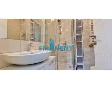 Bathroom equipped with a washbasin, shower cabin, and storage shelves. - image 9