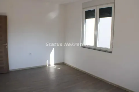 Prazna soba sa belim zidovima, tamnim parketom i prozorom sa roletnama. - image 5