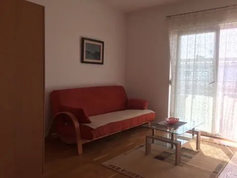Dnevna soba sa crvenom sofom, stočićem i izlazom na terasu. - image 2