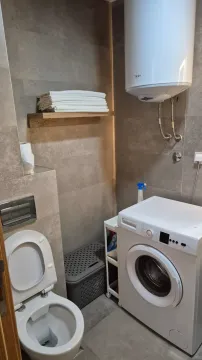 Compact bathroom with a toilet, washing machine, and water heater. - image 25