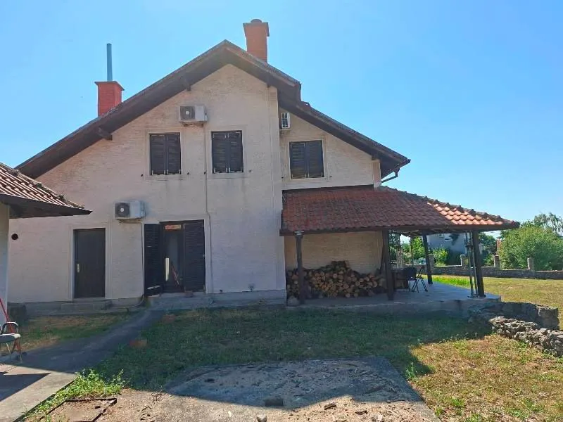 Pogled na zadnju stranu kuće sa natkrivenom terasom i dvorištem.