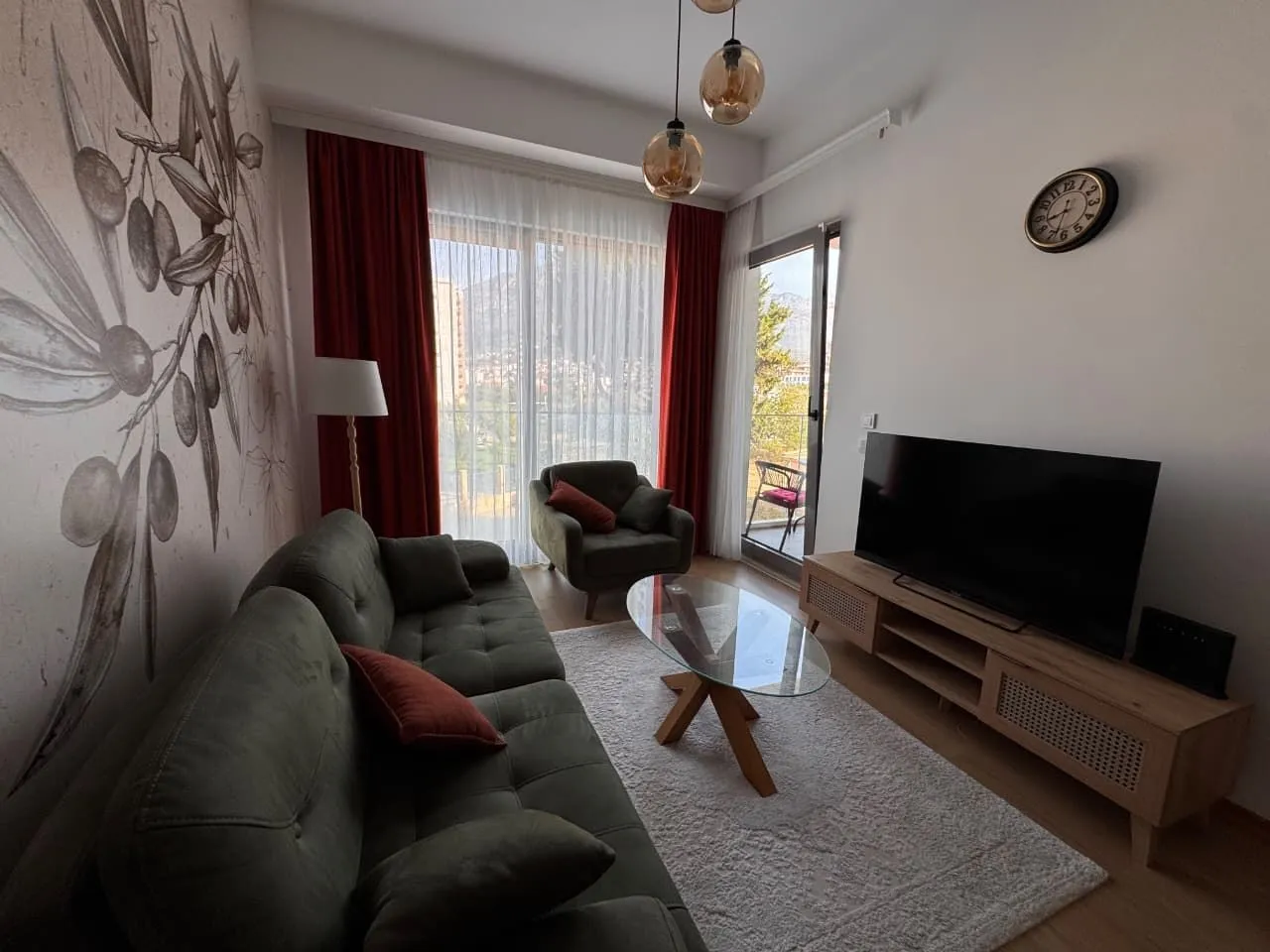 Dnevna soba sa garniturom, televizorom i izlazom na terasu.