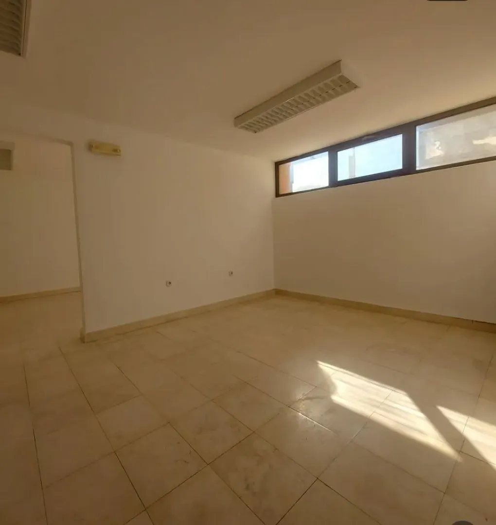 Empty bright room with tiled floors and high-level windows.