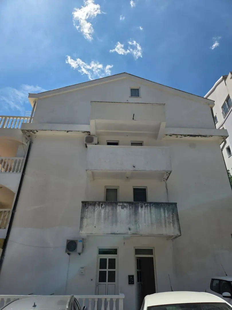 Spoljašnji izgled bijele stambene zgrade sa balkonima.