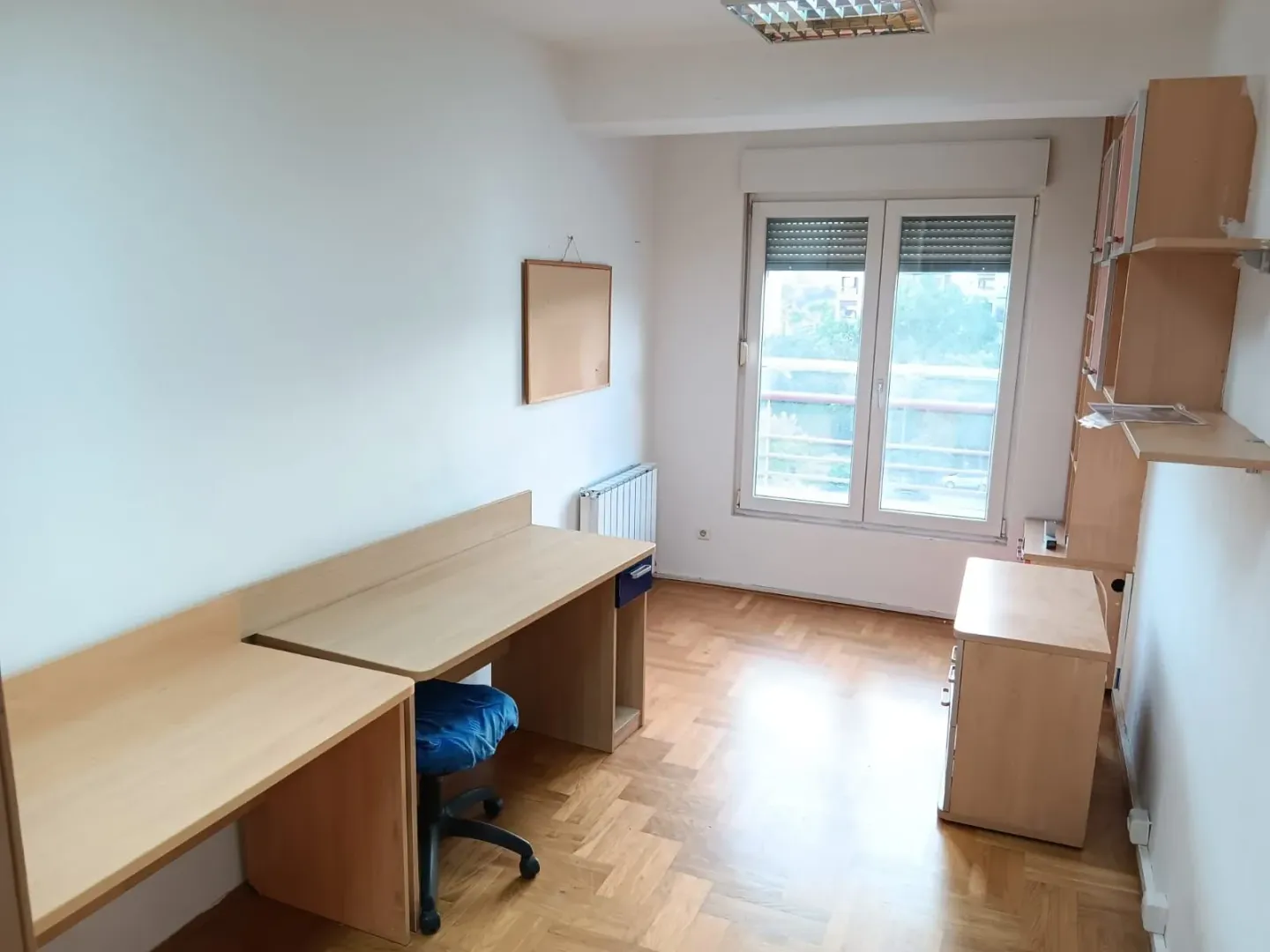 Study room with a desk, shelving units, and parquet flooring.