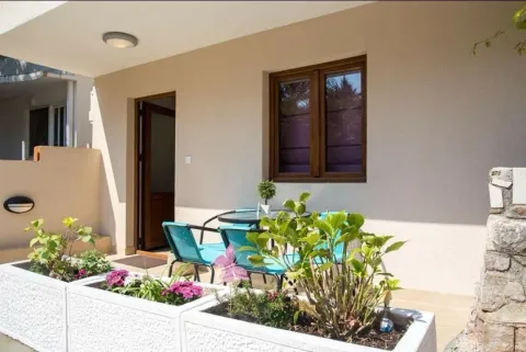 Terrace with a table, chairs, and flower planters in front of the building entrance. - image 2