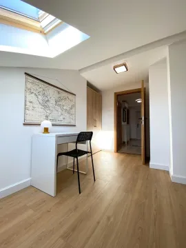 Small room with a desk, chair, wardrobe, and a skylight window. - image 6