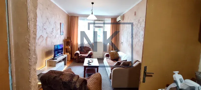 Dnevna soba sa garniturom za sjedenje, televizorom i izlazom na terasu.