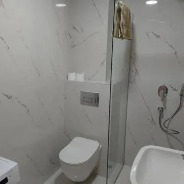 A modern bathroom with white marble tiles and a built-in toilet.