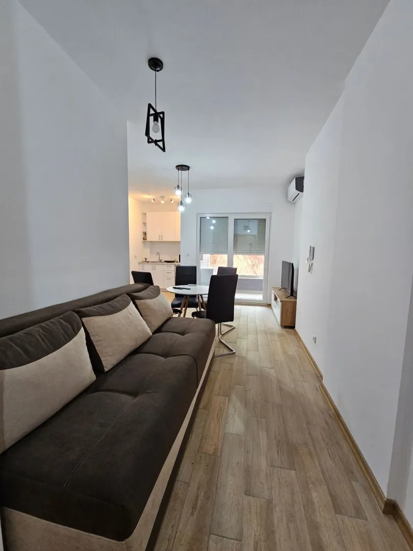 Living room with sofa, dining area and view of the kitchen.