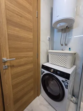 Bathroom with a washing machine, water heater and wooden door. - image 12