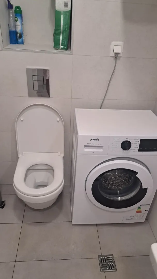 Manje kupatilo sa toaletom i veš mašinom.