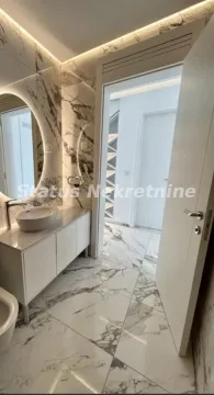 Moderno opremljeno kupatilo sa mermernim pločicama i kružnim ogledalom. - image 11
