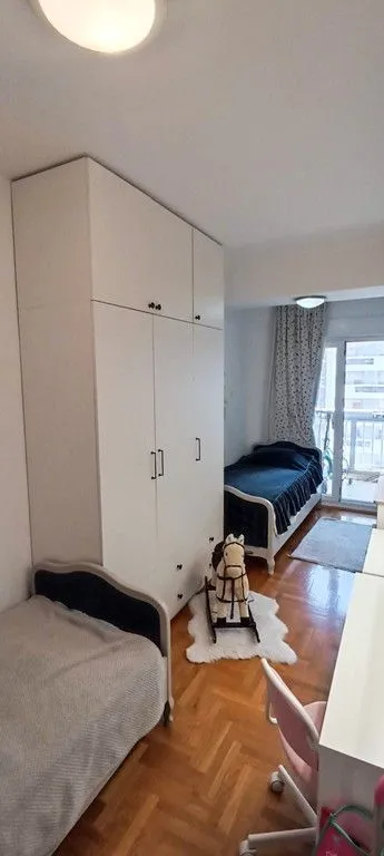 Dječja soba sa krevetima, velikim ormarom i radnim stolom.