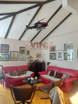 Living room with red sofas and a sloping ceiling with exposed beams. - image 13