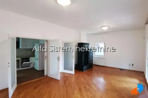 Spacious living room with hardwood floors and a solid fuel stove, looking into the kitchen. - image 6