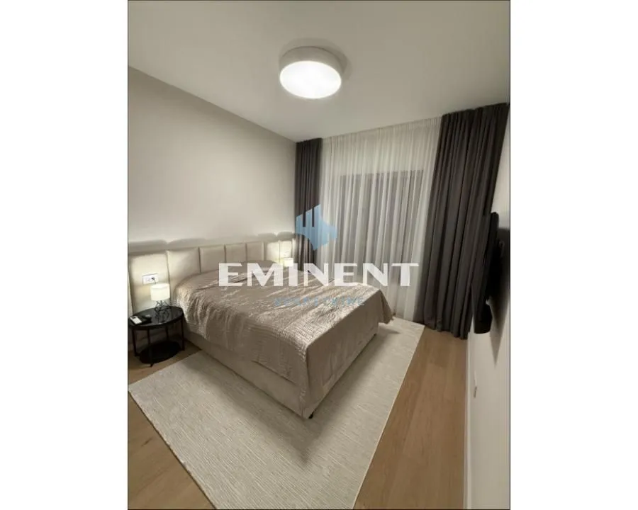 Furnished bedroom with a double bed and a window with curtains.