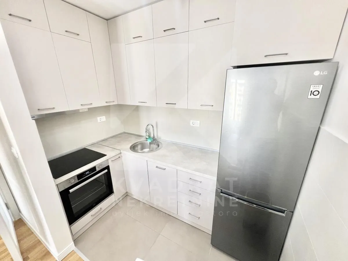 Small equipped kitchen with light-colored cabinetry and a refrigerator.